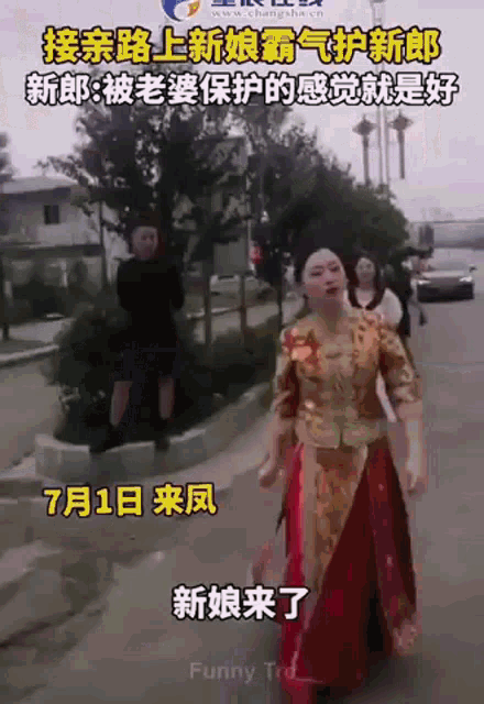 a woman in a red and gold dress is walking down a street with chinese writing on it