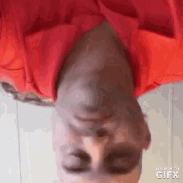 a man in a red shirt is upside down and looking down .