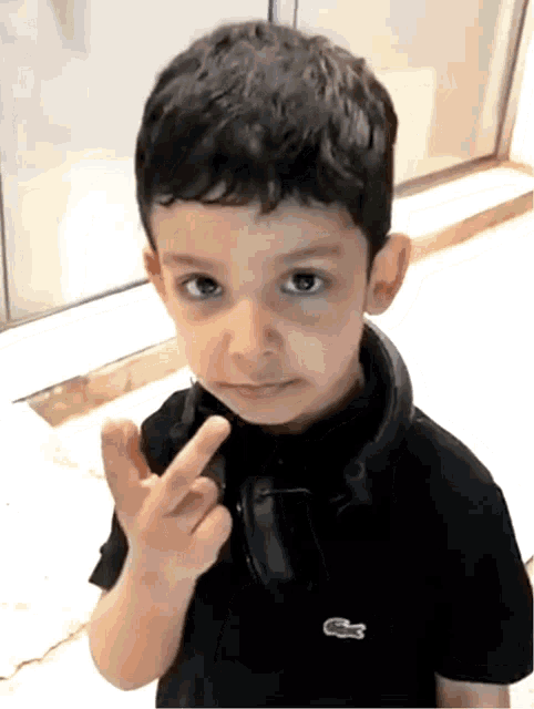 a little boy wearing headphones and a black shirt with a lacoste logo on it