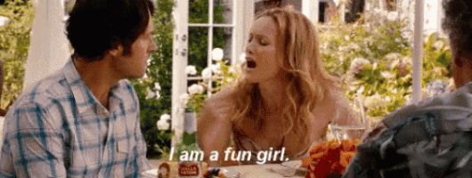 a man and a woman are sitting at a table and the woman is saying `` i am a fun girl . ''