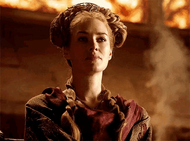 a woman in a braided crown is sitting in front of a fireplace .