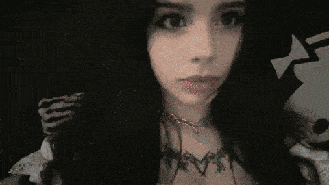 a woman with long black hair and a tattoo on her chest is making a funny face .