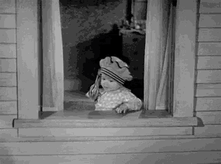 a black and white photo of a child looking out a window