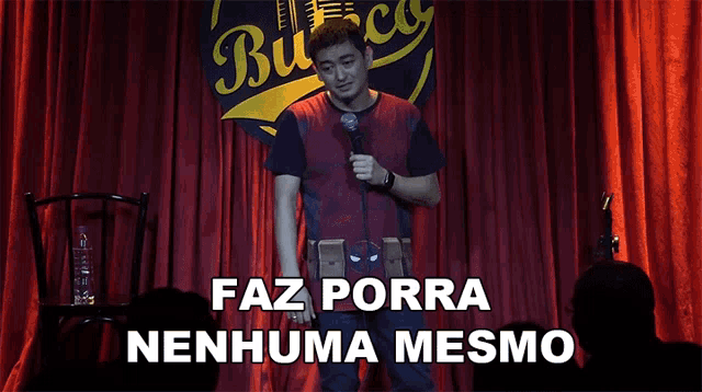 a man stands in front of a microphone with the words faz porra nenhuma mesmo behind him