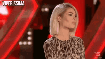 a woman in a leopard print top is standing in front of a red wall .