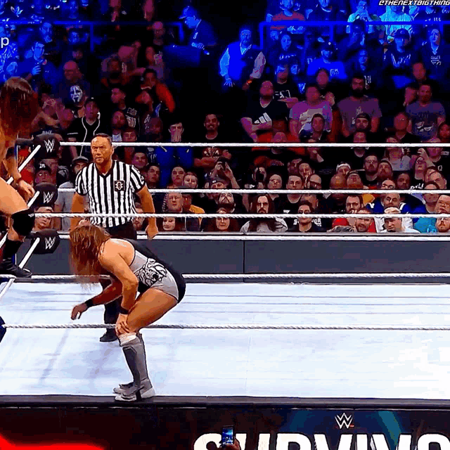 a man in a wrestling ring with a referee and the word survivor in the corner