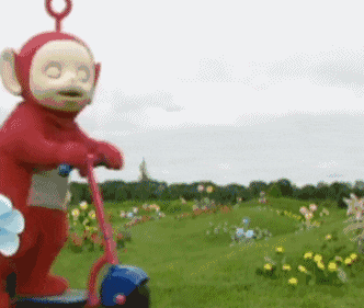 a red teletubbies character is riding a scooter in a field