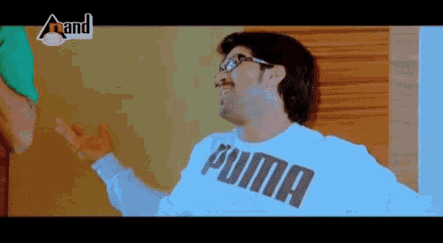 a man wearing a white puma sweatshirt is standing in front of a wall