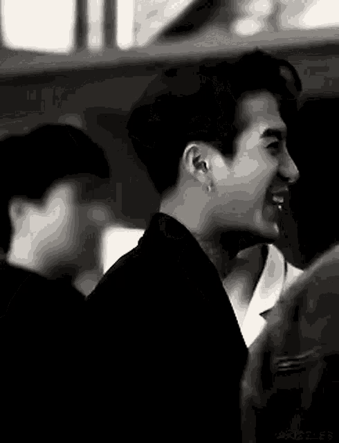 a black and white photo of a young man laughing in a crowd .