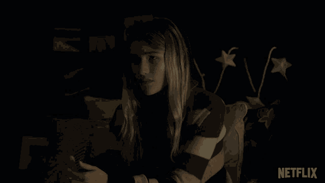 a woman sitting in a dark room with netflix written on the bottom