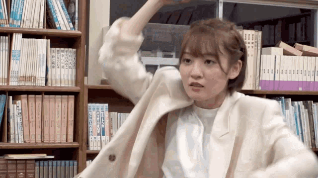 a woman in a white jacket is standing in front of a bookshelf with books on it including one that says ' chinese '