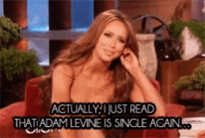 a woman sitting on a red couch with the words actually i just read that adam levine is single again