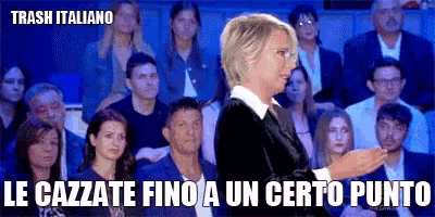 a woman stands in front of a crowd of people and says trash italiano