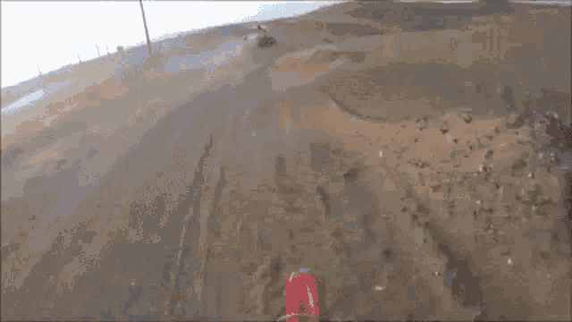 a person is riding a dirt bike on a dirt road and they are wearing a pair of red bull gloves