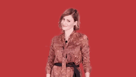 a woman in a floral dress with her arms outstretched on a red background