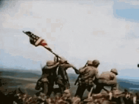 a group of soldiers are standing on top of a hill holding an american flag .