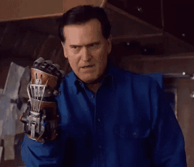 a man wearing a blue shirt is holding a robotic hand