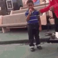 a young boy is singing into a microphone in a church