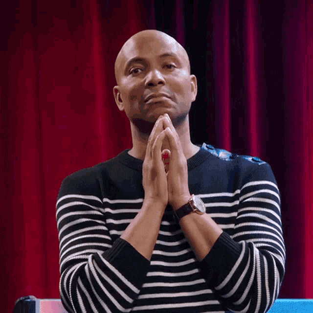 a man in a black and white striped sweater with his hands folded