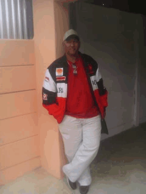 a man leaning against a wall wearing a red and black jacket that says lg