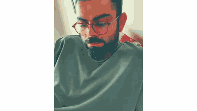 a man with a beard and glasses is wearing a green sweater .