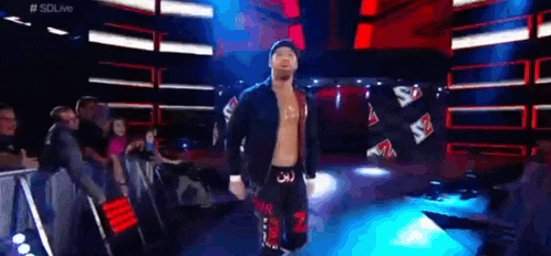 a wrestler is walking down a ramp in a wrestling ring .