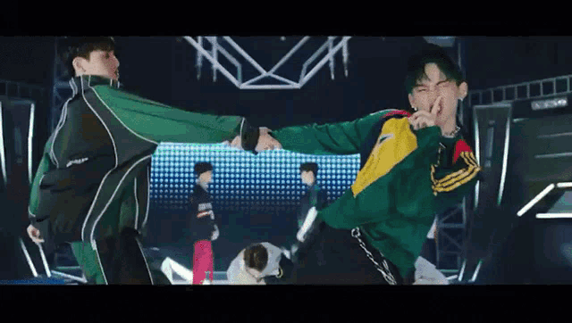 a man in a green jacket is standing next to another man in a yellow and black jacket