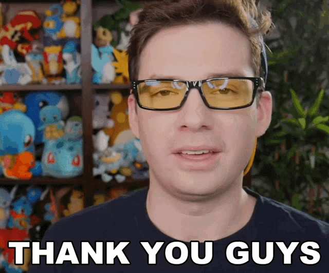a man wearing glasses says thank you guys in front of a shelf full of stuffed animals