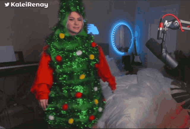 a woman in a christmas tree costume is standing in front of a microphone and keyboard