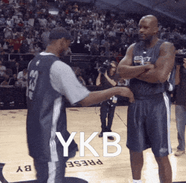 two basketball players on a court with ykb written on the floor