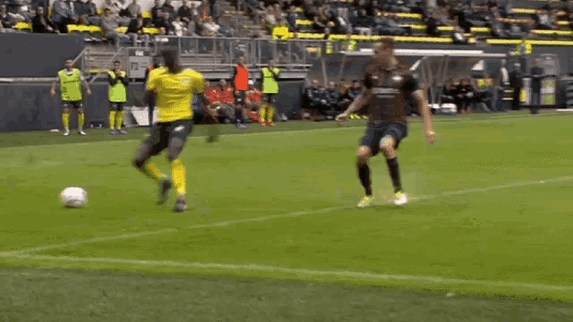 a soccer player in a yellow jersey is kicking a ball