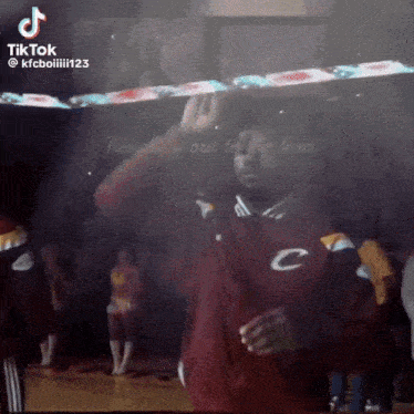 a man in a cleveland cavaliers jacket is dancing in front of a crowd .