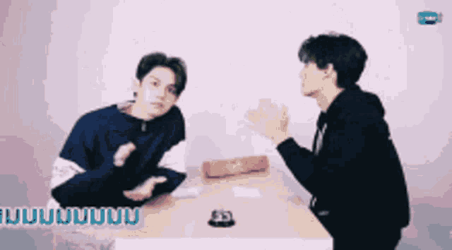 two men sitting at a table with confetti falling around them .