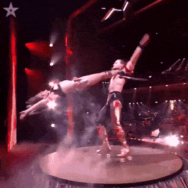 a man and a woman are performing a stunt on a stage with a star in the background