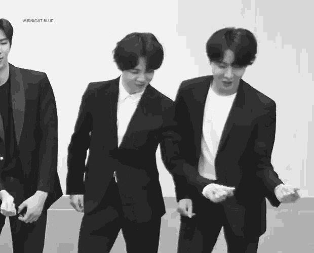 three men in suits are standing next to each other and dancing in a black and white photo .