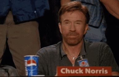 a man is sitting at a table with a sign that says chuck norris