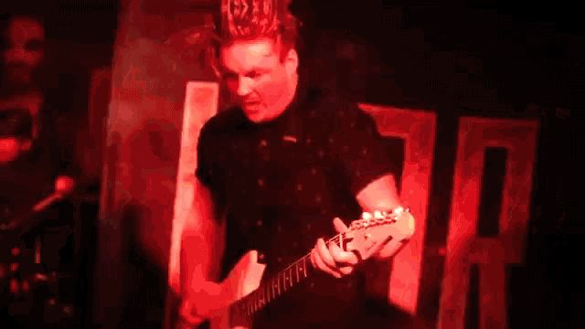 a blurry image of a man playing a guitar in a dark room .