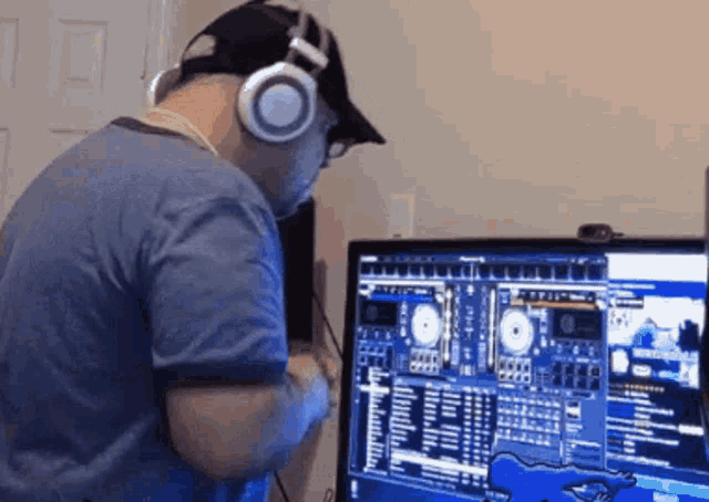 a man wearing headphones and a hat is playing music on a computer