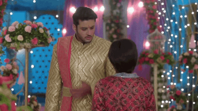 a man and a woman are standing next to each other in a room decorated with flowers and lights .