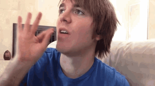 a young man in a blue shirt is giving the ok sign with his hand