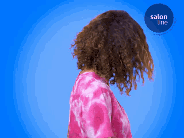 a woman in a pink tie dye shirt is standing in front of a blue background with a salon line logo