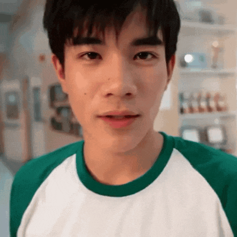 a young man wearing a green and white shirt is looking at the camera