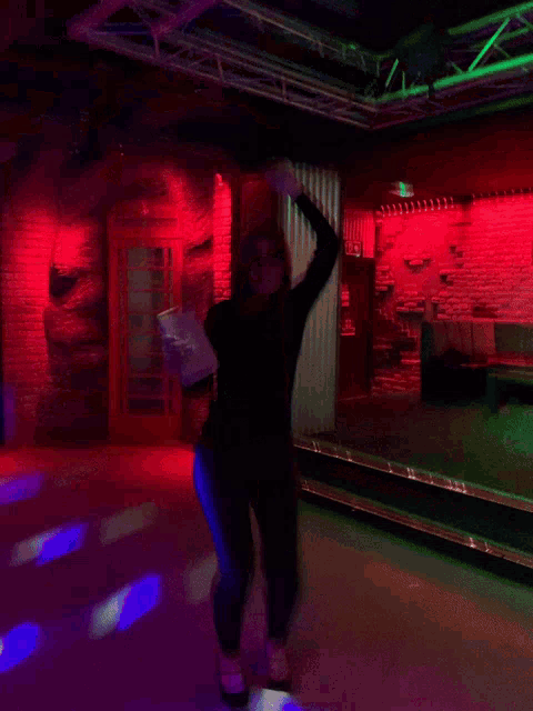a woman in a black dress is dancing in a dark room