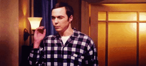 a man in a plaid shirt is standing next to a lamp in a hallway .
