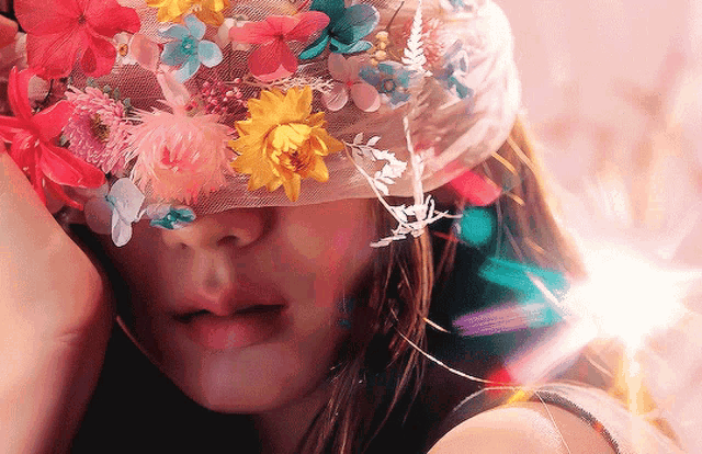 a woman with flowers on her hat covering her face