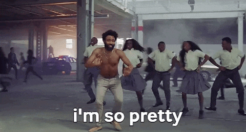 a shirtless man is dancing with a group of people in school uniforms in a parking garage .