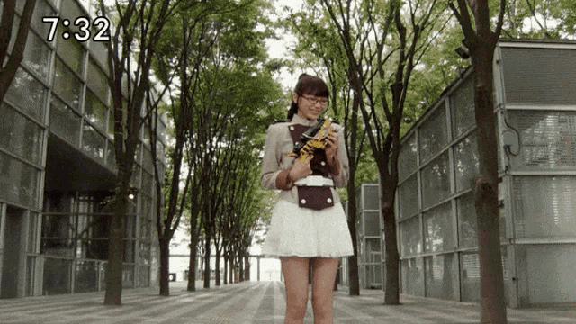 a girl in a white skirt stands in front of a building that says 7:32 on the bottom