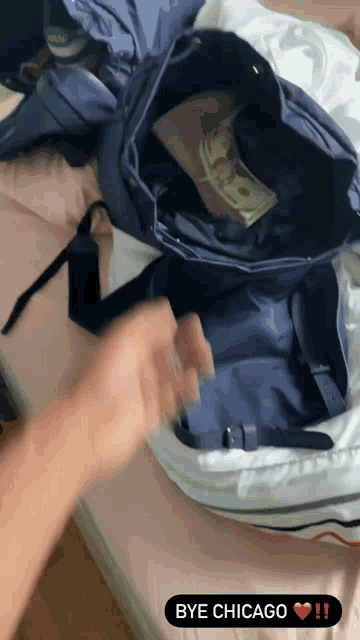 a person is putting money into a backpack that says bye chicago on the bottom