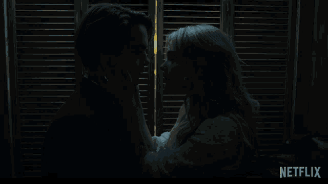 a man and woman kissing in front of shutters with a netflix logo in the corner