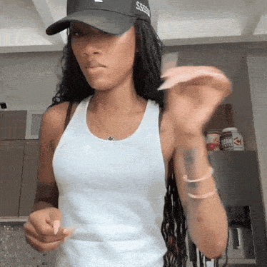 a woman wearing a white tank top and a black hat that says sss on it